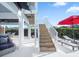 Outdoor patio area with stairs to the second story, lounge chairs, and a view of the lush landscaping at 114 Gull Dr, Anna Maria, FL 34216