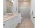 Bathroom featuring double sinks, white cabinets, and a tiled shower with glass doors at 114 Gull Dr, Anna Maria, FL 34216