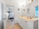 Bright bathroom with double sinks, white cabinetry, and decorative nautical accents, plus a doorway view to the bedroom at 114 Gull Dr, Anna Maria, FL 34216