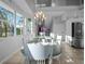 Sunny dining room boasting a large chandelier, staircase, and stainless steel refrigerator at 114 Gull Dr, Anna Maria, FL 34216