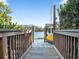 View of the dock and boat lift framed by lush foliage and leading out to tranquil waters at 114 Gull Dr, Anna Maria, FL 34216