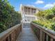 Inviting walkway leading to a charming two-story coastal home with screened porch, framed by lush, mature landscaping at 114 Gull Dr, Anna Maria, FL 34216