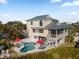 Backyard featuring a two-story home with a lovely pool, lounge seating, and manicured landscaping at 114 Gull Dr, Anna Maria, FL 34216