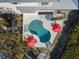 Aerial view of a kidney-shaped pool surrounded by lounge chairs and red umbrellas at 114 Gull Dr, Anna Maria, FL 34216