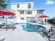 Backyard pool and deck with two-story home with balcony and red umbrellas at 114 Gull Dr, Anna Maria, FL 34216