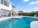 Backyard swimming pool with lounge seating and lush tropical landscaping in the backyard of the home at 114 Gull Dr, Anna Maria, FL 34216