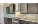 Close-up of kitchen with stainless steel appliances, marble countertops and backsplash, and dark wood cabinetry at 1214 Gulf Blvd, Englewood, FL 34223