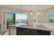 Kitchen island featuring marble countertop, bar sink, and view through a sliding glass door at 1214 Gulf Blvd, Englewood, FL 34223