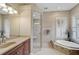 Luxurious bathroom with glass-enclosed shower, soaking tub, double vanity, and shuttered windows at 1227 Tuscany Blvd, Venice, FL 34292