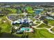 Aerial view features a clubhouse with an outdoor pool, tennis courts, a golf course, and parking at 1227 Tuscany Blvd, Venice, FL 34292
