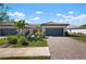 Charming home with a paver driveway, gray garage door, and lush landscaping at 14369 Eagle Branch Dr, Nokomis, FL 34275