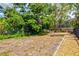 The property features a spacious fenced backyard with mature shade trees, lush plants, and an area for outdoor activities at 424 Cezanne Dr, Osprey, FL 34229