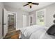 Cozy bedroom featuring a ceiling fan, windows, and hardwood floors, with a glimpse into the bathroom at 1010 E Lake Ave, Tampa, FL 33605