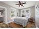 Cozy bedroom featuring a ceiling fan, windows, and hardwood floors, with a glimpse into the bathroom at 1010 E Lake Ave, Tampa, FL 33605