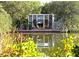 Stunning waterfront home featuring walls of glass, lush greenery, and inviting outdoor seating at 3721 Flamingo Ave, Sarasota, FL 34242