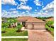 Beautifully landscaped home with a red tile roof, stone accents, and a brick driveway, showcasing curb appeal at 20686 Valprato Ct, Venice, FL 34293