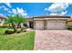 Well-manicured home exterior with a brick driveway, lush green lawn, and charming landscaping at 20686 Valprato Ct, Venice, FL 34293