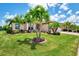 Beautifully landscaped front yard with palm trees, lush green grass, and a well-maintained home exterior at 20686 Valprato Ct, Venice, FL 34293