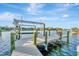 Waterfront property with a boat dock featuring a lift, set against a backdrop of beautiful blue skies and peaceful canal views at 5607 Tidewater Preserve Blvd, Bradenton, FL 34208