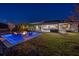 Stunning backyard at night with illuminated pool and patio with a modern fire pit at 3407 155Th E Ave, Parrish, FL 34219
