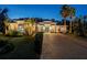 Elegant stucco home showcasing lush landscaping, palm trees, and a stately brick driveway at twilight at 3407 155Th E Ave, Parrish, FL 34219