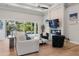 Open-concept living room with wood floors, a cozy fireplace, modern furniture, and views of the outdoor pool area at 3407 155Th E Ave, Parrish, FL 34219