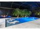 Night view of backyard pool and deck featuring in-pool sun loungers, palm trees, and elegant lighting at 3407 155Th E Ave, Parrish, FL 34219