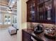 A wet bar with granite countertop, backsplash, and a dark wood cabinet with glass doors, featuring a coffee machine at 4610 Balboa Park Loop, Lakewood Ranch, FL 34211