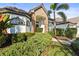 Inviting front entrance with brick accents, lush landscaping, and a covered entryway to the home at 6815 Turnberry Isle Ct, Lakewood Ranch, FL 34202