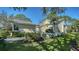 Beautifully landscaped light yellow home with manicured green lawn and mature trees under a clear blue sky at 7628 Whitebridge Gln, University Park, FL 34201