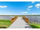 Scenic dock with wooden railings extends over a calm lake under a bright blue sky at 8358 Redonda Loop, Lakewood Ranch, FL 34202