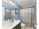 Bright bathroom featuring blue walls, decorative mirror, and stylish patterned shower curtain at 223 Heritage Isles Way, Bradenton, FL 34212