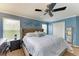 This main bedroom boasts a large bed, ceiling fan, and windows for natural light and an ensuite bathroom at 223 Heritage Isles Way, Bradenton, FL 34212