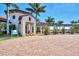 Exterior of the community clubhouse with a covered entrance, brick driveway, and tropical landscaping at 23703 Waverly Cir, Venice, FL 34293