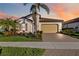 Charming single-story home with a two-car garage, tile roof, and lush tropical landscaping at 23703 Waverly Cir, Venice, FL 34293