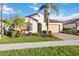 Charming single-story home with a two-car garage, tile roof, and lush tropical landscaping at 23703 Waverly Cir, Venice, FL 34293