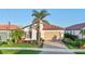 Inviting single-story home with lush landscaping, a red tile roof, and a brick-paved driveway at 23703 Waverly Cir, Venice, FL 34293