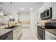 Bright kitchen featuring white cabinetry, granite countertops, stainless steel appliances, and tiled floors at 23703 Waverly Cir, Venice, FL 34293