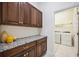 Laundry room with granite countertops and overhead cabinets, next to a separate laundry room with machines at 23703 Waverly Cir, Venice, FL 34293