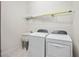 Well-lit laundry room featuring modern washer and dryer units, and a utility sink at 23703 Waverly Cir, Venice, FL 34293