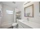 Clean bathroom featuring a shower-tub combo, large mirror, and storage at 2458 Whippoorwill Cir, Sarasota, FL 34231
