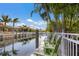 Scenic backyard view with seating overlooking a tranquil canal, palm trees, and clear blue sky at 579 Fore Dr, Bradenton, FL 34208