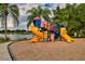 Colorful community playground with slides, ladders, and play area, all next to a scenic lake and mature palm trees at 854 Rosemary Cir, Bradenton, FL 34212