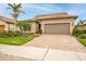 Charming one-story home with a brick driveway, two-car garage, and lush landscaping at 13925 Miranese St, Venice, FL 34293