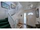 View of foyer with stairway, front door with glass, and tile planter as you enter this charming home at 145 Burns Rd, Terra Ceia, FL 34250