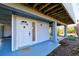 The front entrance has a white door with glass and a transom window above with blue painted porch and wood supports at 145 Burns Rd, Terra Ceia, FL 34250