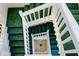 An eye-level view of a staircase with green carpet and white railing at 145 Burns Rd, Terra Ceia, FL 34250