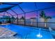 Wide view of screened pool with fountain feature, lush landscaping, and twilight sky at 2930 61St E Dr, Ellenton, FL 34222