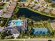 An aerial view of a community pool, tennis courts, and surrounding houses near a pond at 3325 Azurite Way, Bradenton, FL 34211