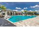 Large outdoor pool with chairs and umbrellas surrounded by palm trees under a sunny blue sky with white clouds at 3325 Azurite Way, Bradenton, FL 34211